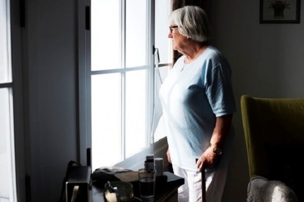 Older lady looks out the window tentatively