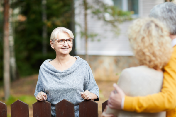 Older woman meeting neighbours over the fence