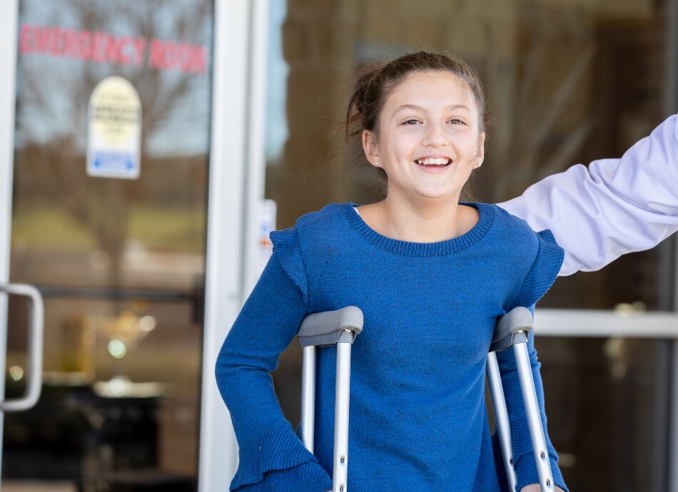 Girl leaving hospital on crutches smiling 