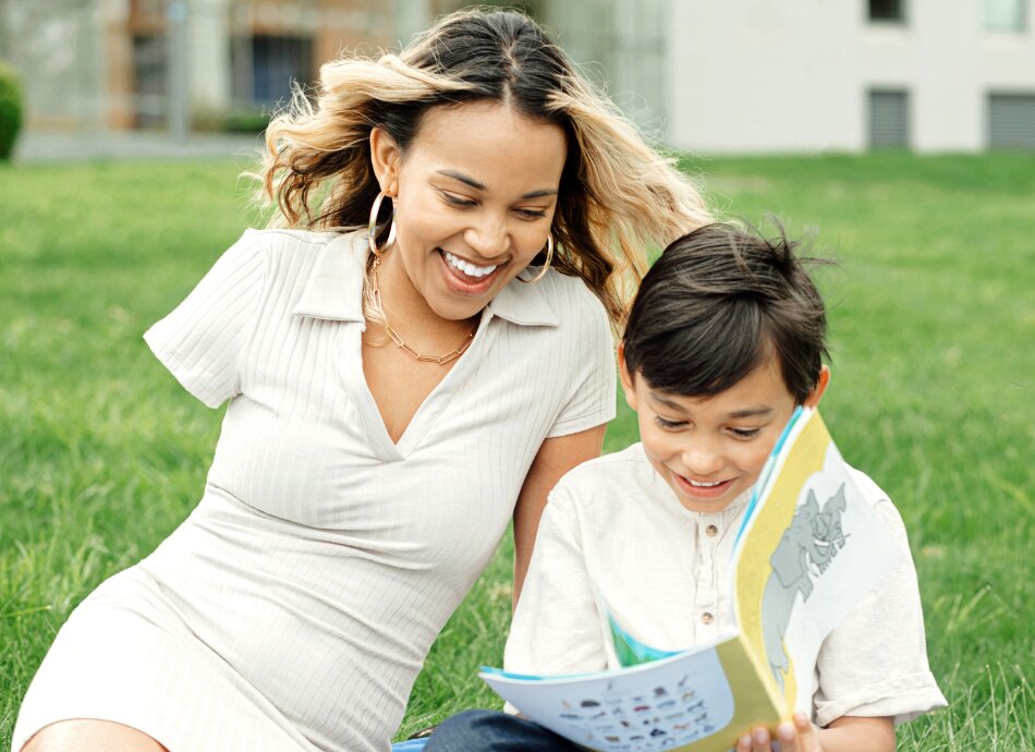 Young woman missing right arm reading outdoors with her son