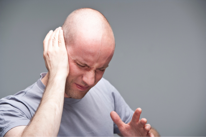 Young man holding right ear with pain or hearing problem