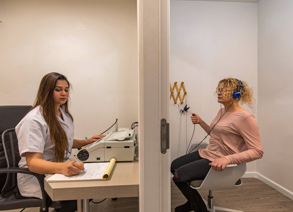 Woman behind a screen with headphones having hearing tested