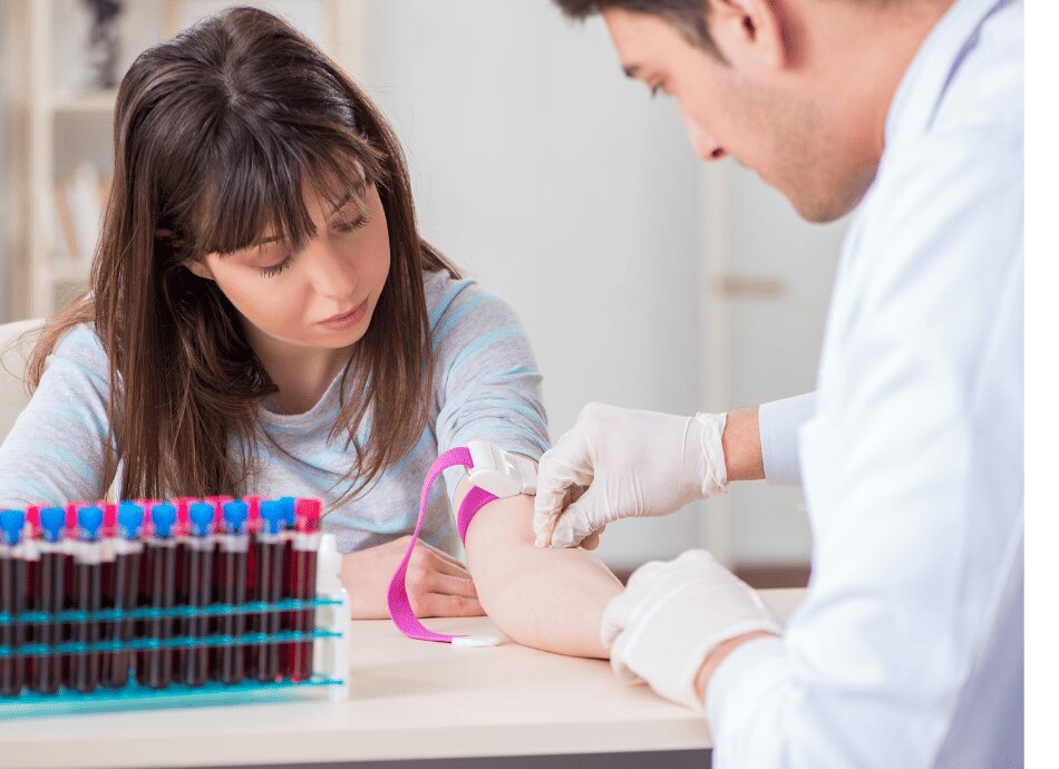 Woman with arm resting on table having blood drawn by healthcare worker