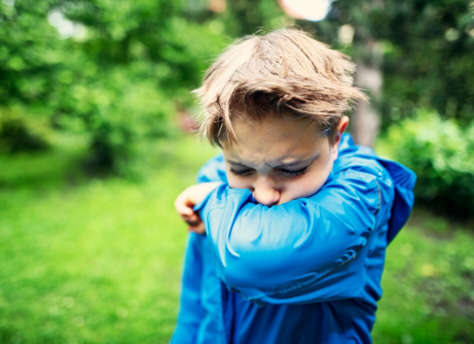 Boy coughing into elbow