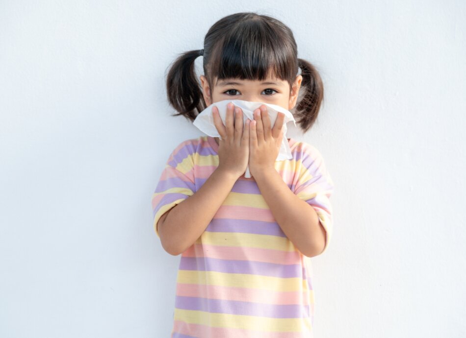 Girl coughing into tissue 