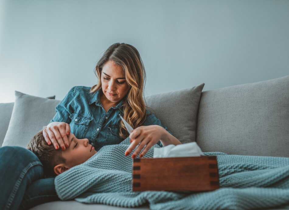 Mother on couch cradles son with high temperature