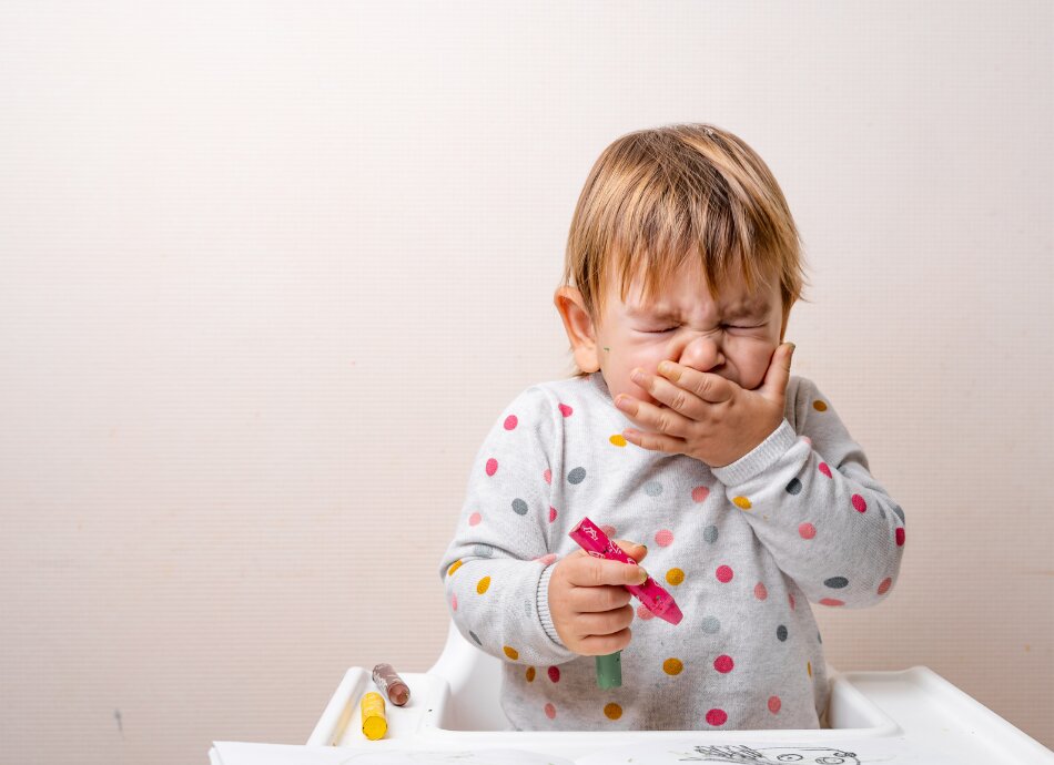 Toddler sneezing with hand over his mouth