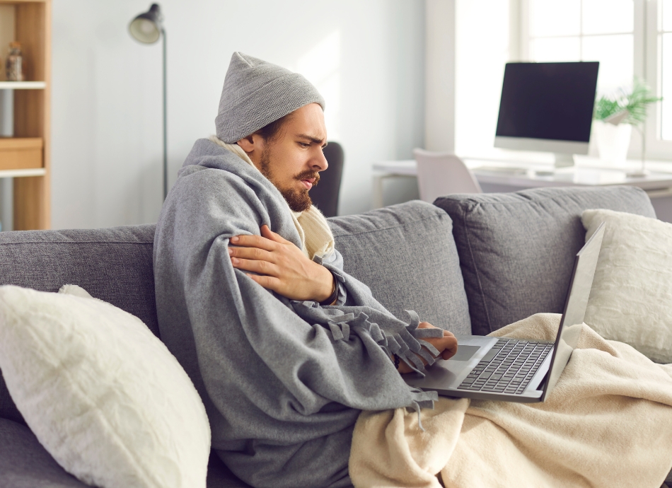 Young man with fever looking at laptop