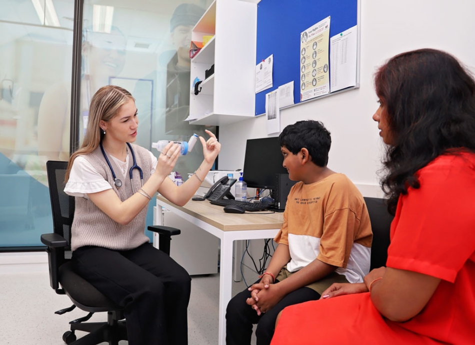 HN 1631 doctor demonstrating use of a spacer to young male with mother looking on 950x690