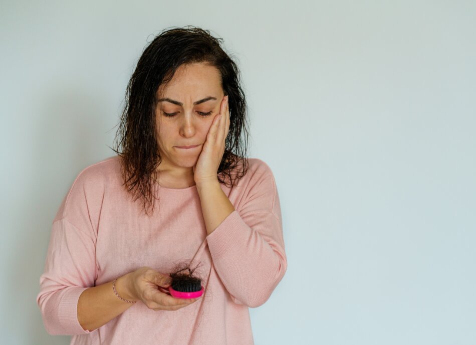 Woman worried about hair loss looking at her brush