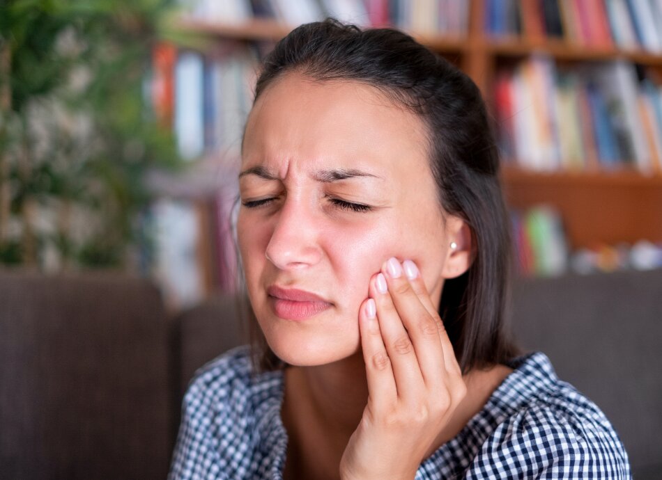 Woman with toothache touches side of cheek in pain