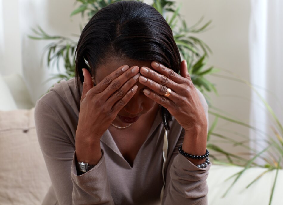 Woman sits with hand on head and severe migraine pain