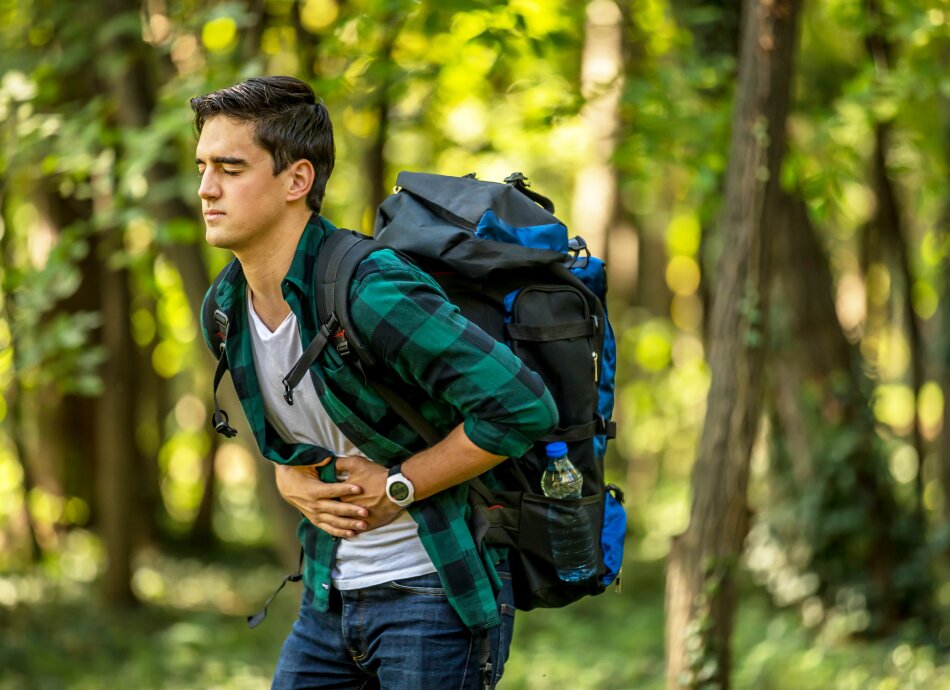 Young man tramping holds stomach in pain