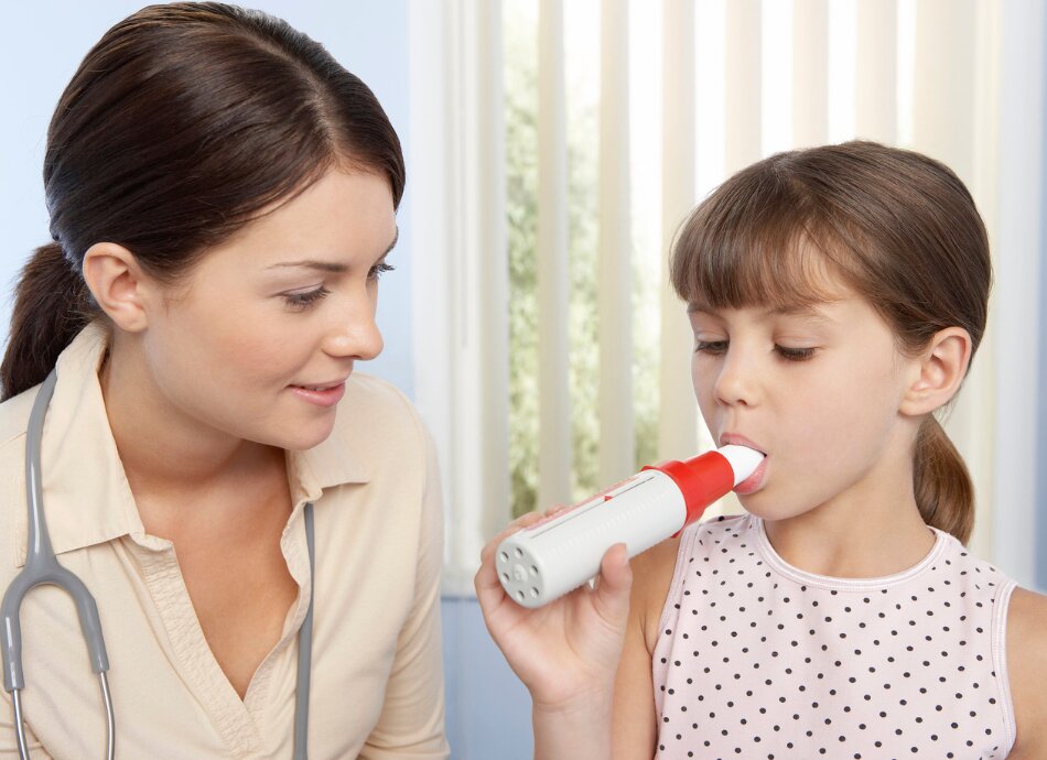 Healthcare professional watches girl blow into peak flow meter