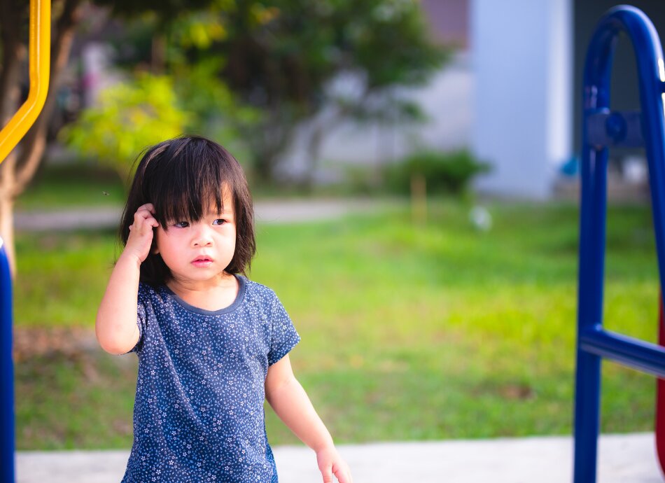 Small girl at the playground scratching her head