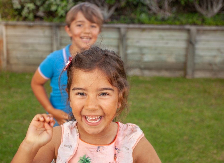 2 children smiling and playing outdoors on the lawn