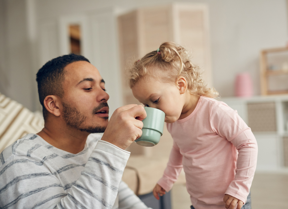 Man helping child take sips from a cup 