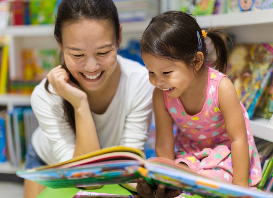 Mum and child reading a book in library