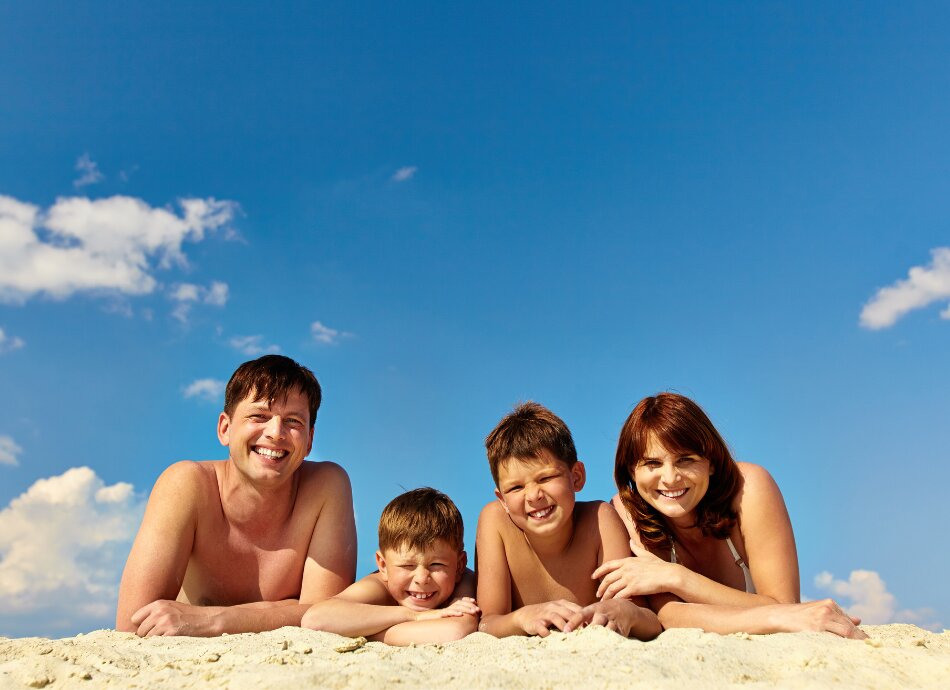 Family lying on the beach in full sun