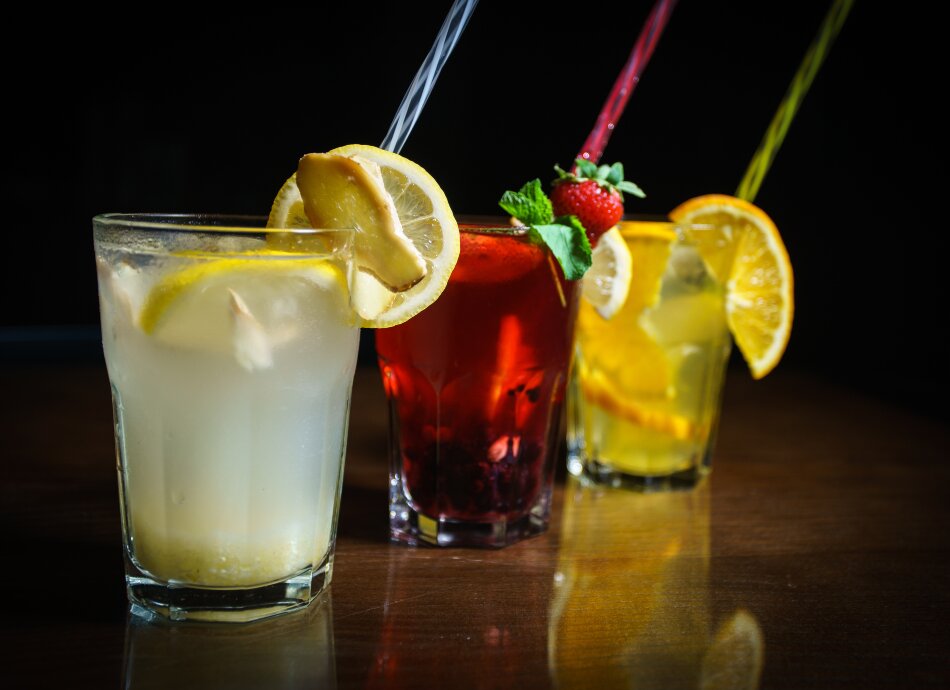 Colourful drinks in glasses with fruit and straws 