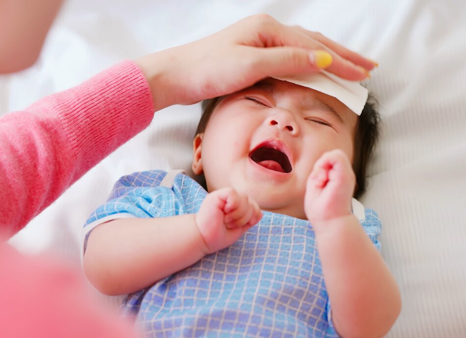 Baby crying while mum wipes brow