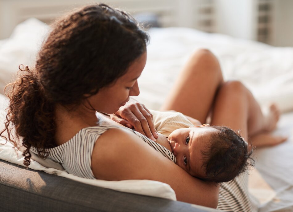 Mother breastfeeding while child looks up