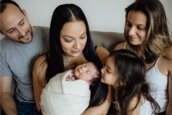 Family sitting on couch and admiring small baby on other's lap