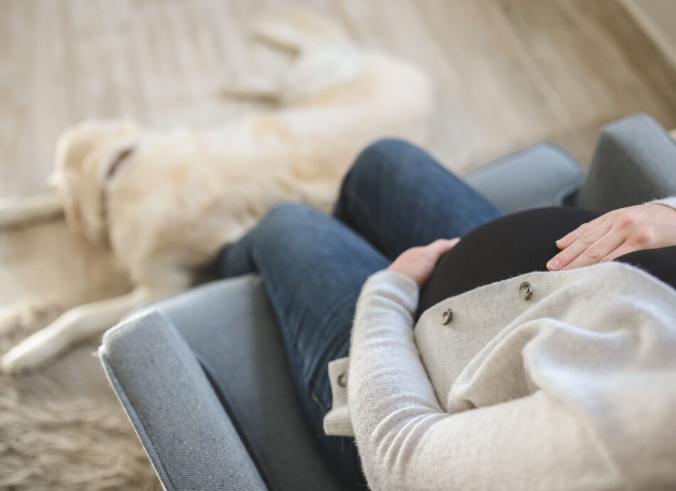 Pregnant woman sitting with dog at her feet