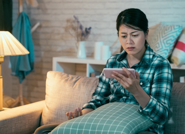 Teenage girl on couch looks worried at something on her phone