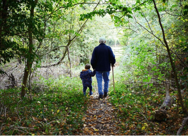 Older man with walking stick outdoors with child