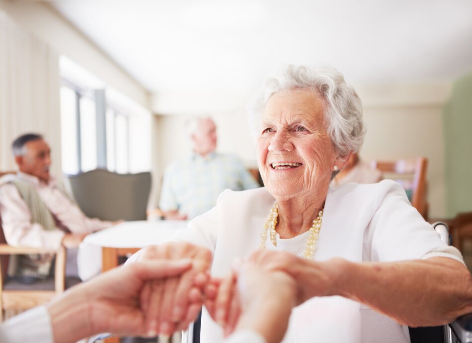 Senior woman holding friend's hands at rest home