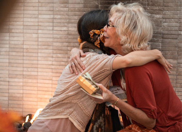 Younger woman hugs older woman after giving her a gift