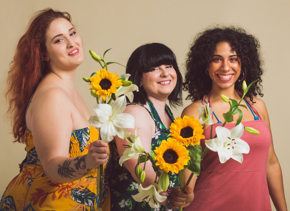 Three larger size woman posing with flowers