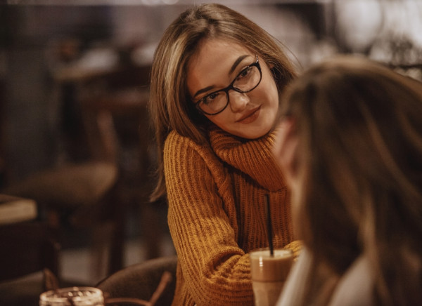 Young woman listening to her friend at cafe