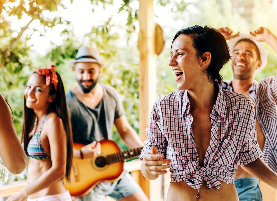 Happy young people at a party playing guitar and dancing