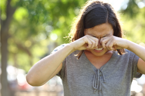 Woman outdoors with itchy eyes rubbing them