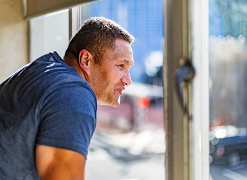 Pensive Māori man looking out of window 