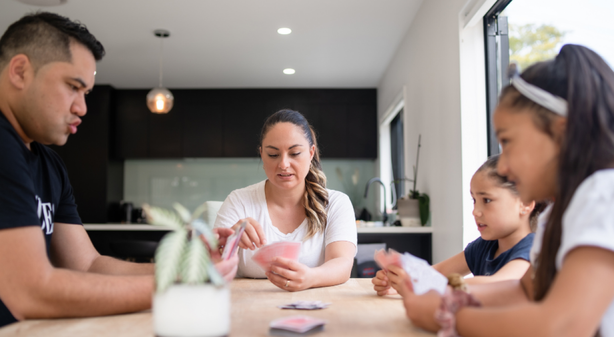 Whanau playing cards around table