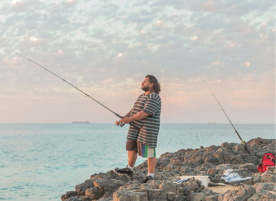 Man fishing off a rock by the sea