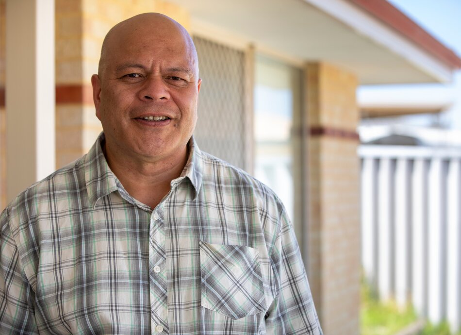 Smiling Pasifika man outside his home